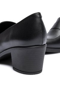 Pair of black leather low-heeled shoes with rounded toe and stacked block heel on a white background.