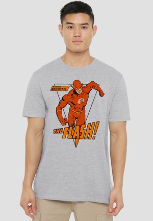 Young man wearing gray t-shirt featuring vintage comic-style Flash superhero running with text "The Flash!" in orange and black.