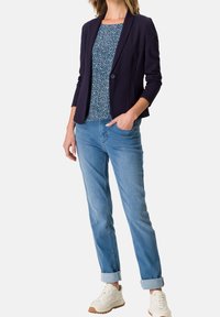 Marinblå blazer, blommönstrad topp, ljusblå jeans och vita sneakers. Texturerat tyg, figursydd design, strukturerad siluett, avslappnad look.