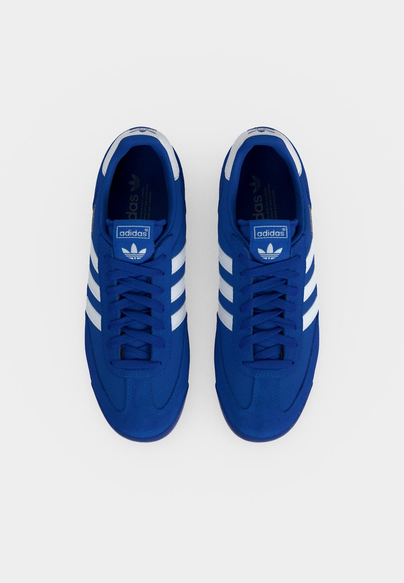 Een paar blauwe Adidas sneakers met witte strepen, veters gestrikt, gezien van boven op een effen witte achtergrond.