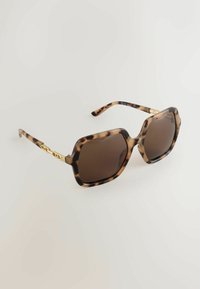 Ochelari de soare cu model de țestoasă, lentile maro, ramă octogonală robustă și accent din lanț auriu pe tample. Textură netedă, finisaj lucios.