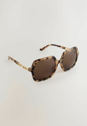 Sluneční brýle s želvovinovým vzorem a hnědými čočkami, mohutný osmihranný rám a zlatý řetízkový detail na nožičkách. Hladká textura, lesklý povrch.