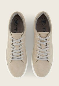 Zapatillas de ante beige con lengüeta de malla, cordones grises y suelas de goma blanca. Diseño plano con detalles de costura minimalistas.