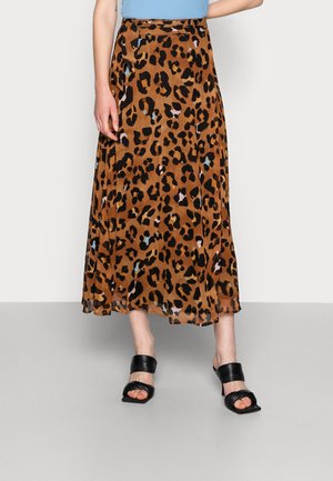 Bruine midi-rok met luipaardprint, gecombineerd met zwarte sandalen met hak en een lichtblauw topje, afgebeeld van taille tot voeten.