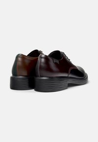 Zweifarbige Lederschuhe mit glänzendem Finish; dunkelbraun und burgunderrot, Gummisohle mit strukturierten Details und runder Zehenform.