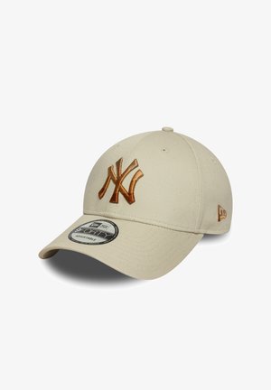 Beige cap made of cotton fabric featuring an embroidered brown "NY" logo, a curved visor, and an adjustable strap at the back.