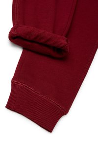 Bordowe bawełniane spodnie dresowe z podwiniętym mankietem, charakteryzujące się prążkowaną fakturą i widocznym przeszyciem wzdłuż szwów.