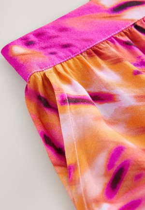 Pogled od blizu na oblačilo z nabranim tkanjem, ki prikazuje živahen vzorec vezave barv v roza, oranžnih in vijoličnih odtenkih z vidnim šivom.