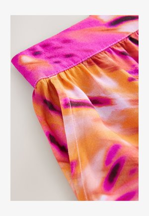 Pogled od blizu na oblačilo z nabranim tkanjem, ki prikazuje živahen vzorec vezave barv v roza, oranžnih in vijoličnih odtenkih z vidnim šivom.