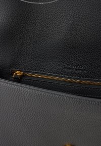 Interno della borsa in pelle nera con base grigia, zipper dorato e testo in rilievo "pelle originale". Finitura testurizzata in tutto.