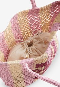 Bolso de mano tejido redondo en rosa y beige con un acabado texturizado. El cierre interno con cordón presenta un pouch beige sólido con un botón decorativo.