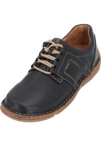 Zapato de cuero negro con detalles en marrón, diseño de cordones, costuras decorativas y suela de goma texturizada. Superficie lisa con punta redonda.