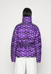 Paarse gewatteerde jas met een overal grafisch patroon, voorzien van een hoge kraag en een getailleerde taille voor een aansluitende pasvorm. Gladde textuur.