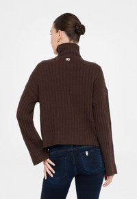 Maglione brown con coste, collo alto e cuciture delle spalle drop. Presenta un logo sul collo e dettagli delle maniche aderenti. Vista posteriore mostrata.