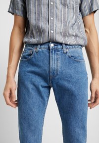 Blå denimjeans med klassisk rak passform, som har fem fickor, metallknap stängning och subtil blekt struktur.