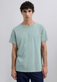 Licht mintgroene katoenen T-shirt met een ronde halslijn en korte mouwen, met een klein logo-detail op de borst. Eenvoudig en casual ontwerp.