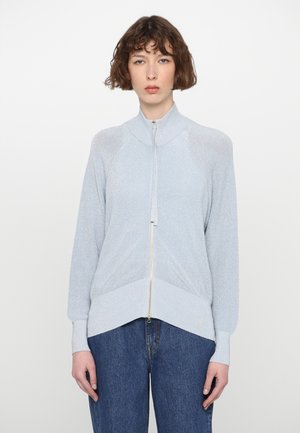 Light blue zip-up cardigan with a high collar, ribbed texture, and fitted cuffs. Features a gold zipper and a chevron hem detail.