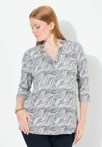 Hemdbluse mit durchgehender Knopfleiste in einem weißen Grundton und einem filigranen Muster aus navyblauen Wirbeln und Punkten. Langärmlig, mit Reverskragen und Seitenschlitzen für mehr Bewegungsfreiheit.