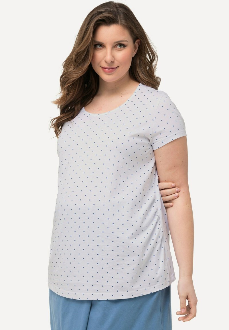Top corto bianco a maniche corte con pois blu, scollatura rotonda e arricciature laterali, abbinato a pantaloni blu. Tessuto di cotone morbido.