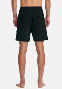 Black swim shorts made of lightweight fabric. Features a back pocket with a flap, a relaxed fit, and a smooth texture. No patterns visible.