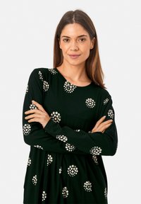 Černé šaty s dlouhým rukávem, kulatým výstřihem a vzorem krémových teček. Vyrobeny z měkké tkaniny, mají volný střih.