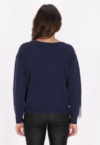 Navyblauer gestrickter Pullover, lockere Passform mit weiten Ärmeln. Ausgestattet mit strukturiertem Stoff und metallischen Fransen an den Ärmeln.