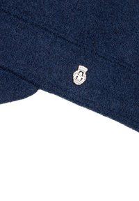 Navyblaue Wollmütze mit strukturiertem Oberflächenmaterial und silbernem Emblem auf der Vorderseite. Strukturdesign mit abgerundeten Kanten.