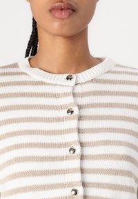 Strickjacke mit beige-weißen horizontalen Streifen, runder Ausschnitt, sechs glänzenden Knöpfen und geripptem Muster.