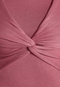 Triko z měkké mauve látky s krouceným detailem na přední straně; hladká textura a přiléhavý střih.