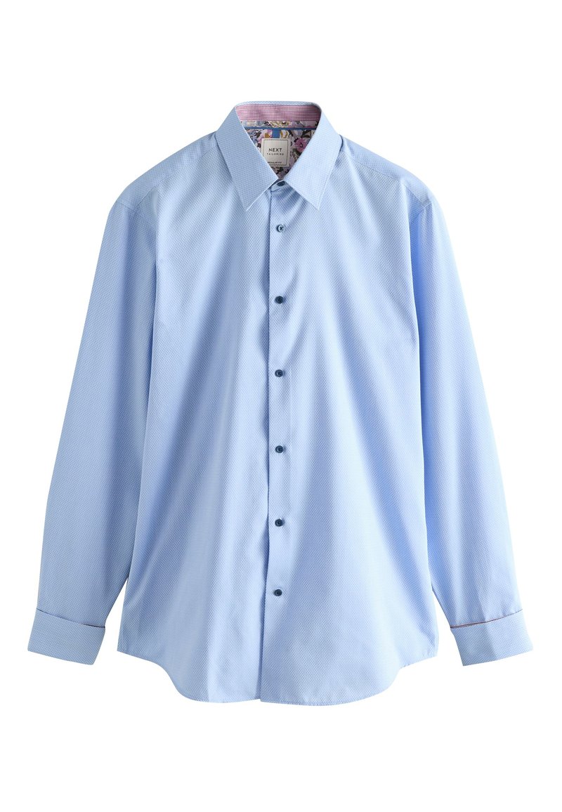 Chemise bleu clair à manches longues avec un motif texturé, col pointu, devant boutonné, boutons bleus, et imprimé floral à l'intérieur du col.