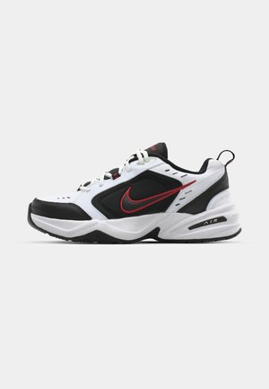 Weiße und schwarze Sportschuhe mit roten Akzenten, aus Mesh- und Synthetikmaterial, runder Zehenpartie, dicker Sohle und auffälliger Markenkennzeichnung an der Seite.
