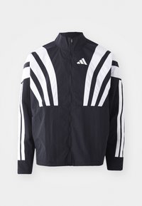 Veste noire avec un col montant, fermeture éclair sur toute la longueur et de larges rayures blanches diagonales sur les manches. Fabriquée en tissu léger avec une texture lisse.