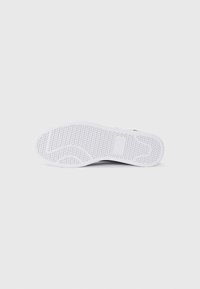 White sneaker outsole with textured grip pattern and logo. Rounded toe, smooth edges, and consistent color across the entire surface.