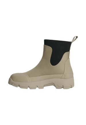 Beige ankelstøvle med tyk, mønstret sål og sort elastisk øvre krave med træk-flig ved hælen.
