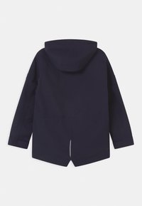 Giacca impermeabile navy con cappuccio, maniche lunghe e orlo curvato. Presenta un design minimalista e un dettaglio riflettente sul retro.