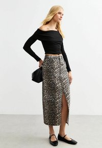 Svart off-shoulder långärmad topp i kombination med en leopardmönstrad knä-length kjol med en framklippning, kompletterad med svarta ballerina-skor och en väska.