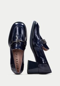 Marina patenterade läderloafers med klack, med en silverfärgad detalj och en slät, glänsande yta.