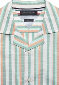 Koszula na guziki z krótkim rękawem w paski w kolorach miętowym, koralowym i białym. Posiada kołnierz typu spread i lekko fakturowaną tkaninę z dwoma guzikami.