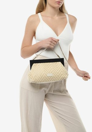 Bolso de mano en tono beige con un patrón de zigzag y un acento negro en la parte superior, que cuenta con una correa de cadena. El material parece texturizado y suave.