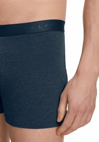 Boxer blu scuro realizzati in un tessuto morbido e elastico con una cintura nera liscia decorata con un logo in rilievo.