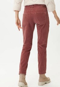 Pantalon en velours côtelé couleur rose poudré, coupe droite avec poches arrière, tissu texturé, associé à des bottines beiges.