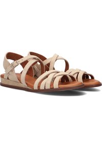 Beige suède sandalen met meerdere kruislings over elkaar lopende banden, bruine leren binnenzool, platte zool en een gespsluiting op de enkelband.