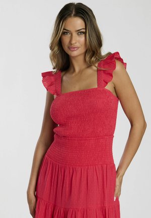 Rotes, geschmücktes Kleid mit Rüschenträgern und einem gestuften Rock. Hergestellt aus leichtem Stoff, der eine subtile Textur aufweist und einen taillierten Oberteil hat.
