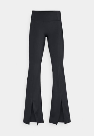 Black flared leggings made from stretchy, smooth fabric. Features a high waistband and slits at the lower leg.