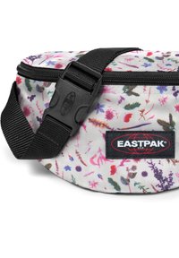 Ledvinka s bílým květinovým potiskem, černým zipem a sponou a s logem Eastpak. Vyrobena z odolné látky s texturovaným povrchem.