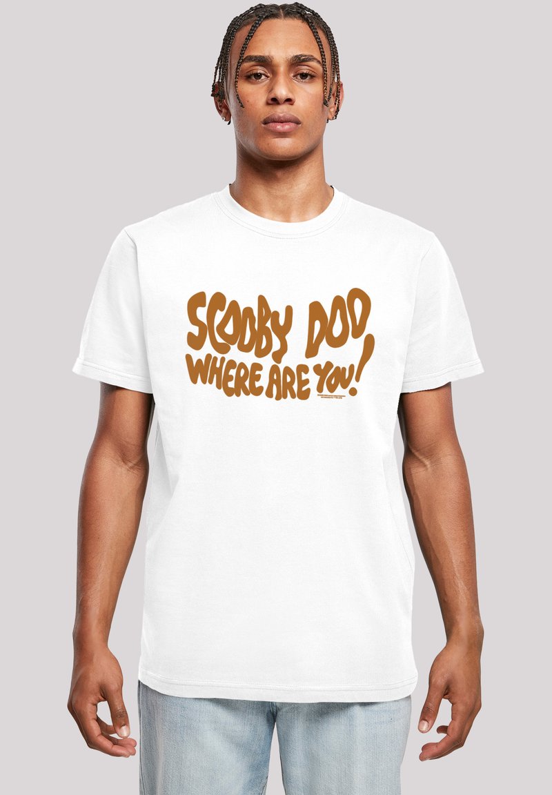 Bílý bavlněný tričko s výrazným hnědým textem, který říká "SCOOBY DOO KDE JSI!" ve hravém, nepravidelném písmu.