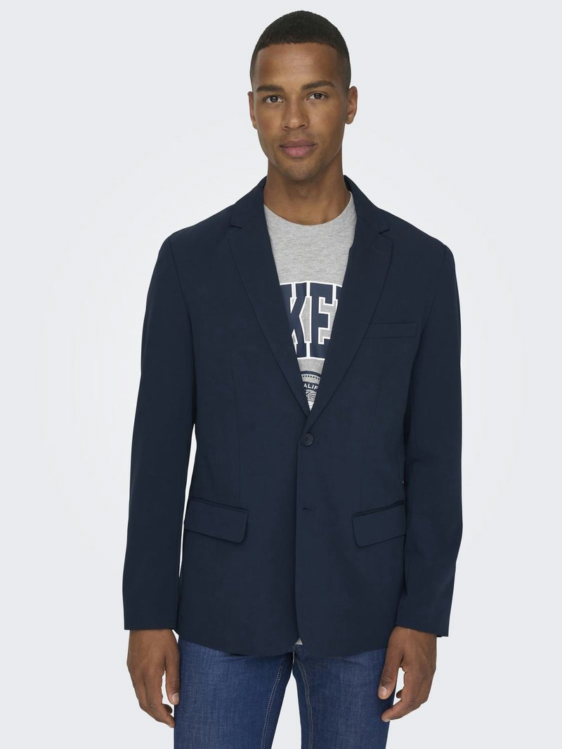 Blazer blu navy realizzato in tessuto leggero, con chiusura a un bottone, due tasche frontali e una texture liscia. Indossato sopra una maglietta grigia.