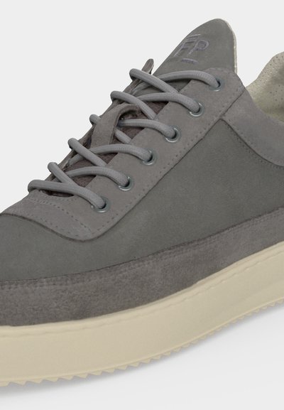 Gros plan d'une basket en daim gris avec des lacets assortis, des œillets métalliques et une semelle épaisse en caoutchouc blanc cassé.