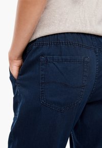 Marina blå byxor av mjukt tyg med resår i midjan och en enda bakficka med subtila sömnadsdetaljer.