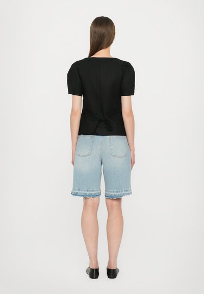 Svart kortermet topp med firkantet halslining, tettsittende design og knytedetalj bak, kombinert med lyseblå denimshorts.